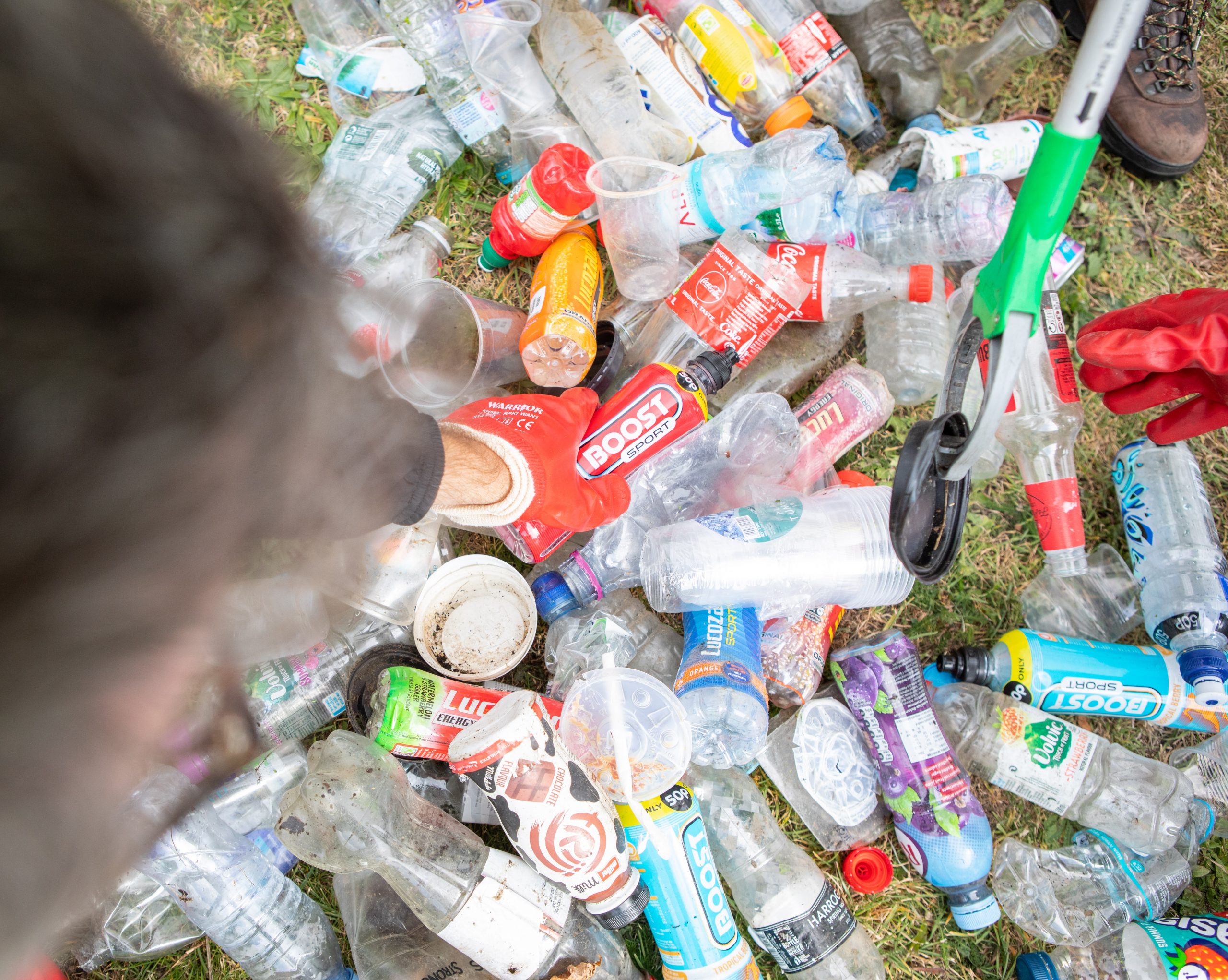 Close up of bottles and litter and cans with hand picking up a bottle
